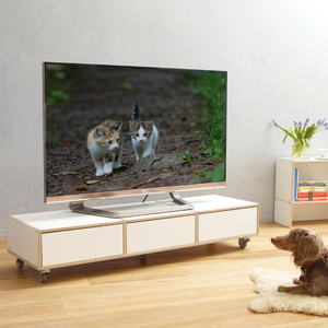 Weißes TV-Board aus Holz auf Rollen mit Schubladen.